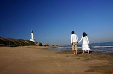 Couple at the beach walking towards the lighthouse