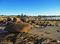  Early morning view of large rocks and sand at the waterfront