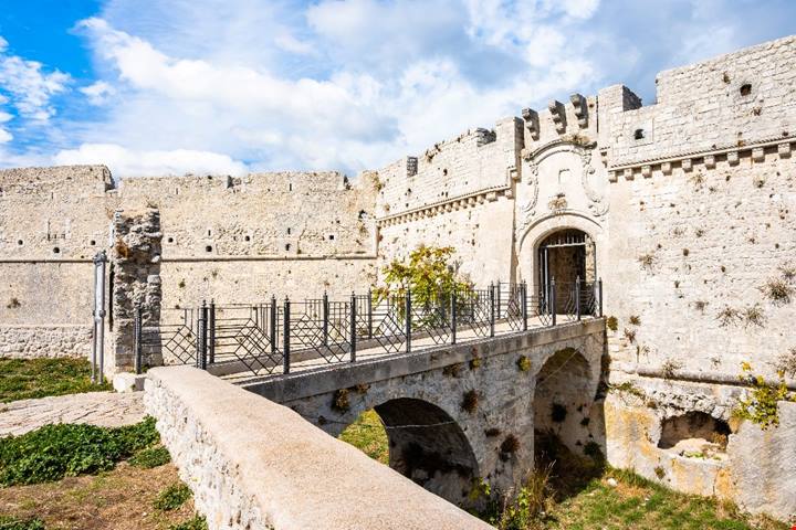 In Puglia esiste una città bianca sospesa tra cielo e mare: la sua grotta sacra attira pellegrini da tutto il mondo