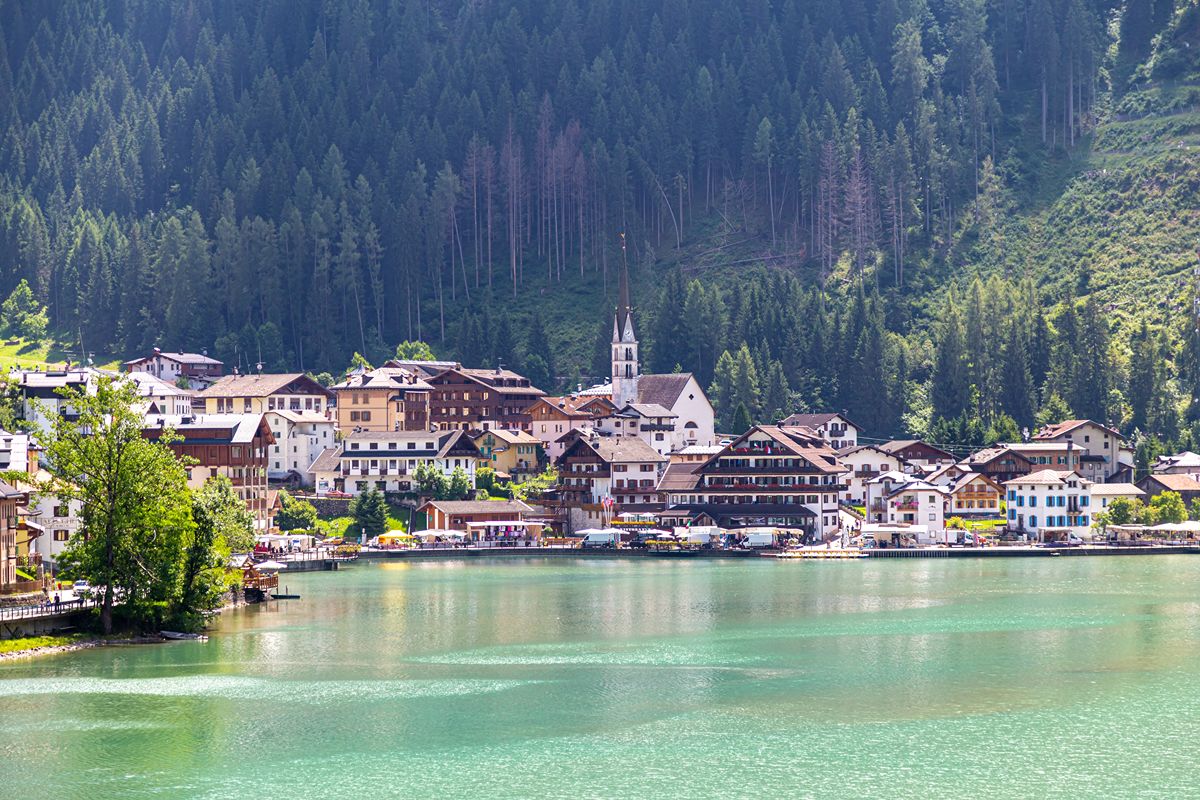 Il villaggio alpino dove il lago riflette le case e la montagna sembra entrare nel paese