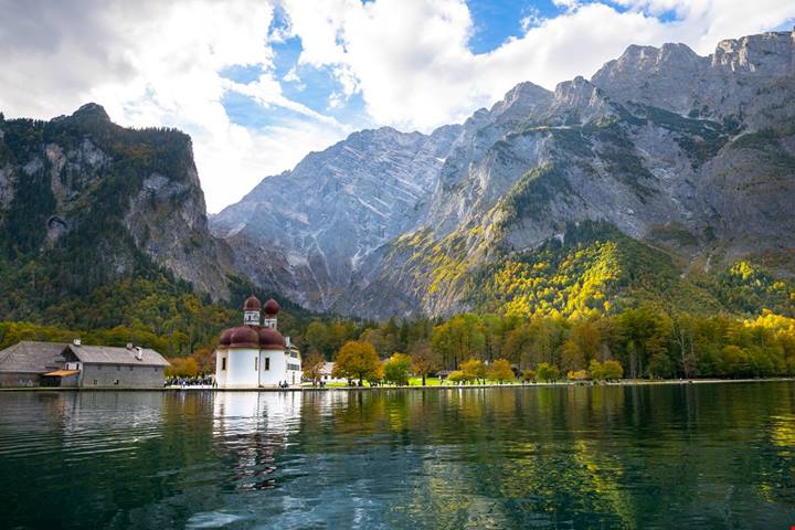 Una chiesetta bianchissima che si riflette sul lago: è la cartolina di un luogo amatissimo dai Re