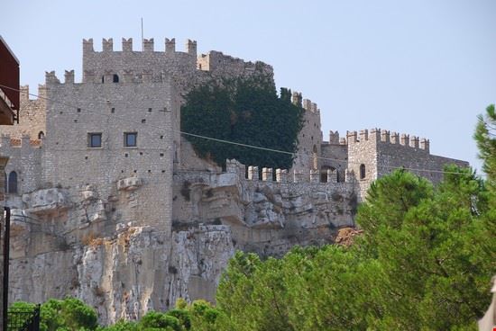 Castello di Caccamo Il Castello di Caccamo è impiantato al culmine di una grande rupe calcarenitica a dominio del centro abitato e di un magnifico teatro paesaggistico costituito dalle propaggini della valle del fiume San Leonardo (oggi per gran parte occupata dal bacino artificiale della diga Rosamarina) e dalle prime balze del monte Calogero.La rupe d'impianto presenta pareti precipiti sui versanti di nord, est ed ovest, mentre sul versante meridionale scoscende con inclinazione costante. Su questo versante sono impiantati, infatti, sia l'orto cintato del maniero sia il sottostante quartiere della Terravecchia, il borgo dal quale - per successive espansioni - si è generato il paese. Da qualsiasi versante li si guardi, il centro abitato e il castello si fondono felicemente con il paesaggio naturale circostante caratterizzato da rupi, boschi e coltivazioni di vario tipo.  