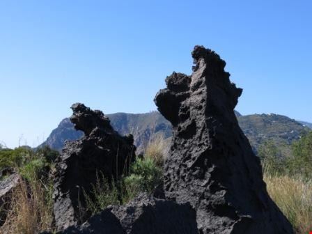  In primo piano due blocchi di rocce vulcaniche della Valle dei Mostri, sullo sfondo l'isola di Lipari Matteo Bertuletti Matteo Bertuletti